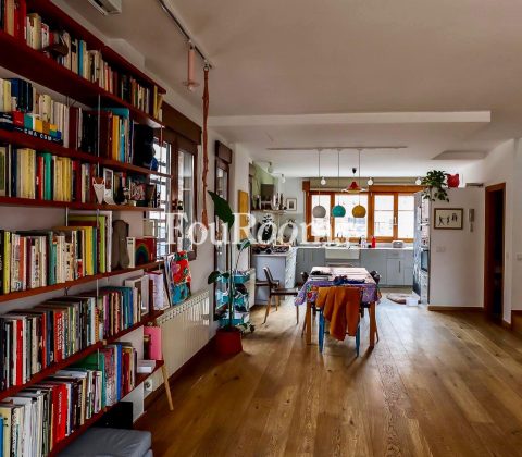 ámplia habitación con estanterías de libros y cocina al fondo
