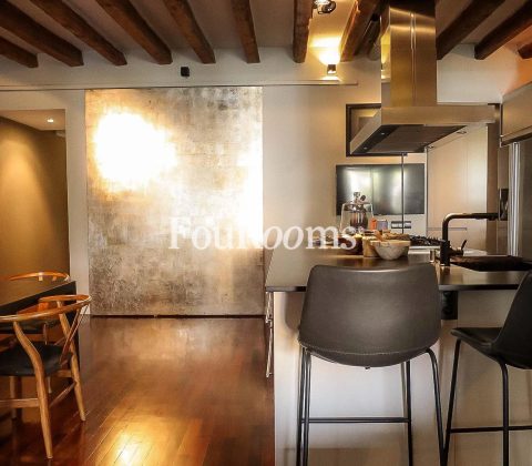 cocina con sillas altas, muebles modernos y pared metálica