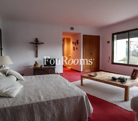 dormitorio con cama grande, suelo con moqueta roja y ventanal