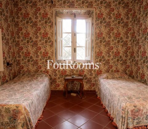 dormitorio con dos camas y papel de flores en las paredes