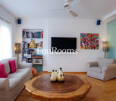 salón con sofá gris, butaca y mesa de madera redonda