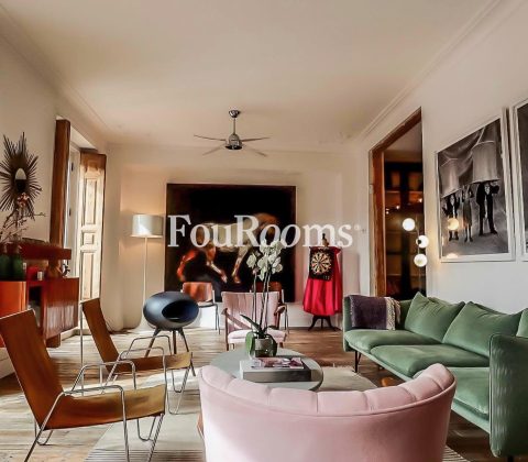 salón con sofá verde, butacas rosas y ventanales